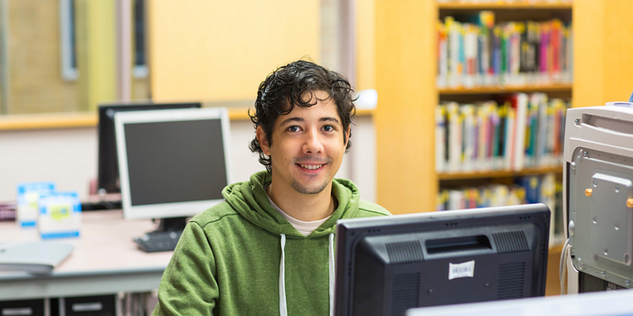 Picture of a Centennial College student in the Story Arts Centre library working on a computer